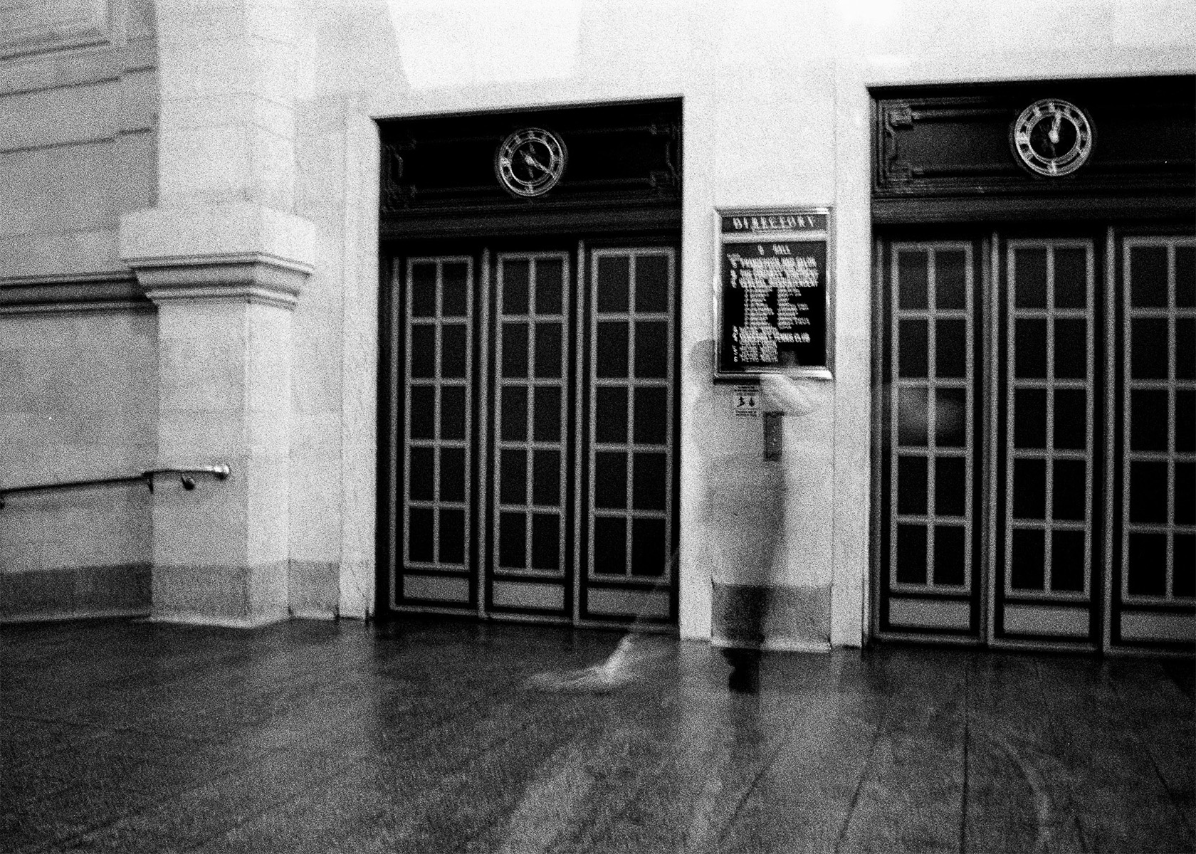 faded custodian mopping by two elevators