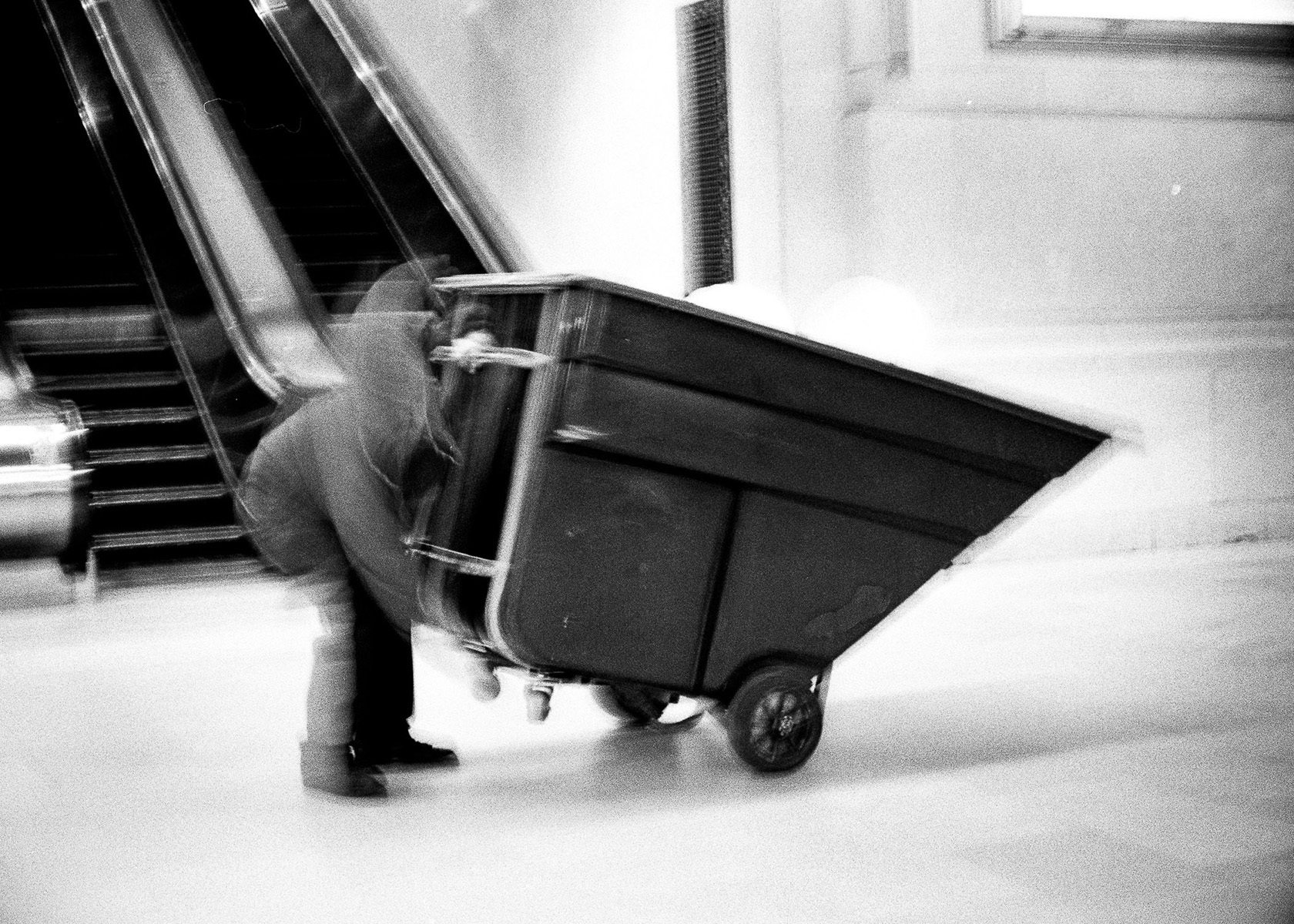 custodian in motion loading a commercial dumpster