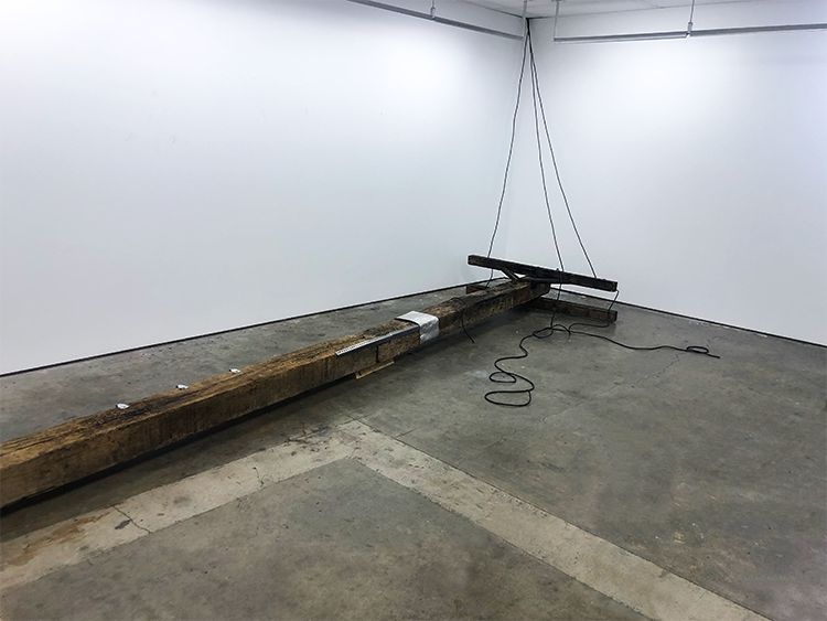 A theatrical downed powerline connected to the wall of the gallery.