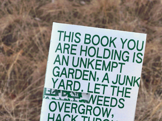 A book cover against a patch of dead grass. The cover reads, 'This book you are holding is an unkempt garden, a junkyard. Let the weeds overgrow, hack through [the fences].' Its text is green, printed on newsprint. A sliver of the cover is cut out, revealing a green pattern in the interior.