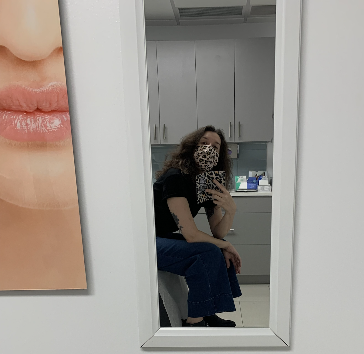 mirror selfie and i'm in a dermatologist office sitting in the patient chair and there's a stock image of a white woman with perfect skin and probably perfect hair lol